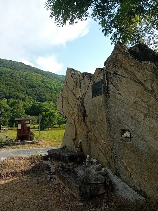 Targa commemorativa della 106° Brigata Giordano Velino immersa nella natura, con una montagna sullo sfondo.