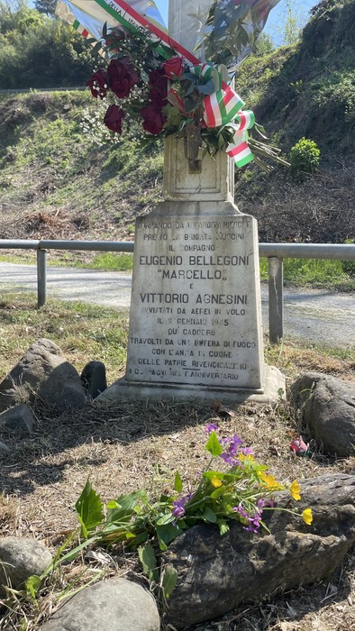 Cippo commemorativo dedicato a Eugenio Bellegoni e Vittorio Agnesini, con fiori e nastri tricolori.