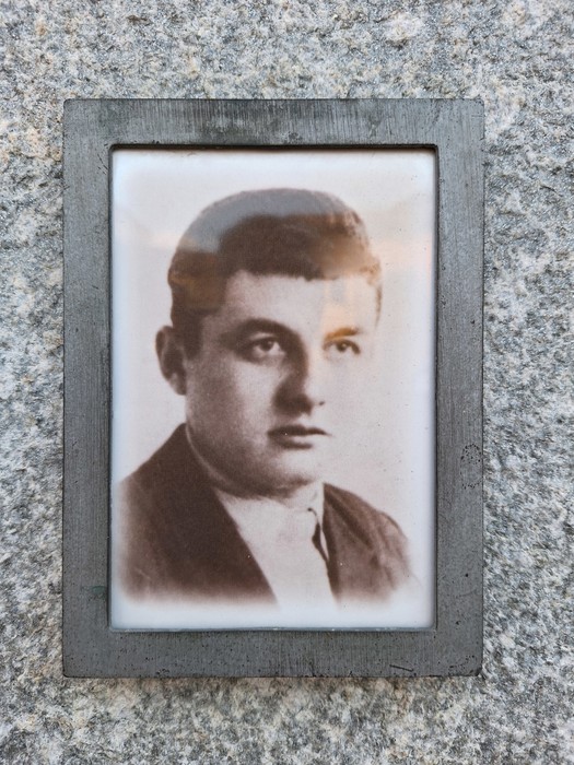 Ritratto di un uomo giovane inserito in una lapide, con sfondo di granito.
