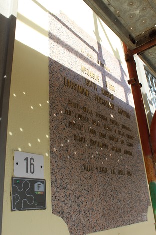 Lapide commemorativa dedicata a Gotti e Larsimont Pergameni, su sfondo murario.