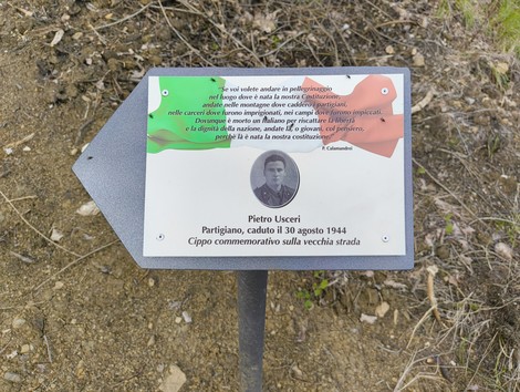 Cippo commemorativo dedicato a Pietro Uscieri, partigiano caduto il 30 agosto 1944, con bandiera italiana sullo sfondo.