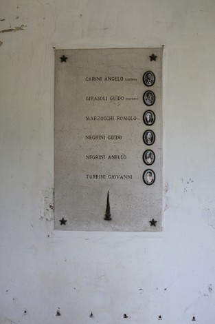 Sacrario ai Caduti Partigiani di Piumazzo con un elenco di nomi su una tavola commemorativa.