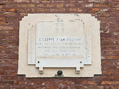 Lapide commemorativa dedicata a Giuseppe Franceschini, situata su un muro di mattoni.