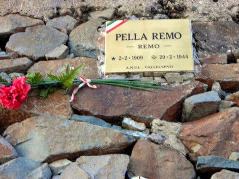 Targa commemorativa in onore di Remo Pella, situata a Pella, con fiori e decorazioni tricolori.