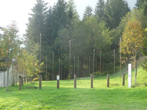 Monumento ai Dodici Caduti immerso nel verde, con pali verticali che simboleggiano i caduti.
