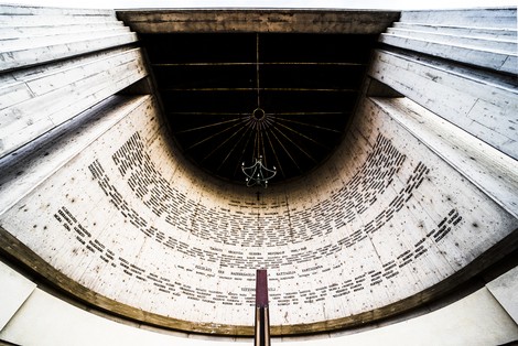 Monumento ai Caduti, struttura commemorativa con incisioni, luce che filtra dall'alto e design architettonico evocativo.
