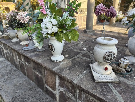 Vasetti di fiori e commemorazioni in un sacrario dedicato ai caduti, atmosphere di rispetto e memoria.