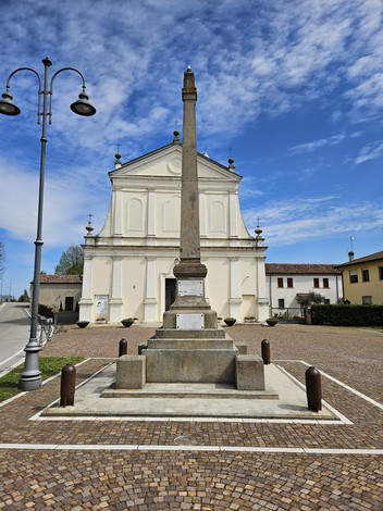 Monumento ai Caduti di Bosaro con obelisco, piazza e edifici storici sullo sfondo, sotto un cielo nuvoloso.