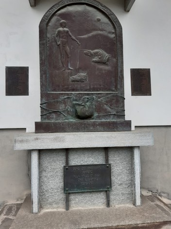 Monumento ai partigiani georgiani con rilievi e iscrizioni commemorative su base in pietra.