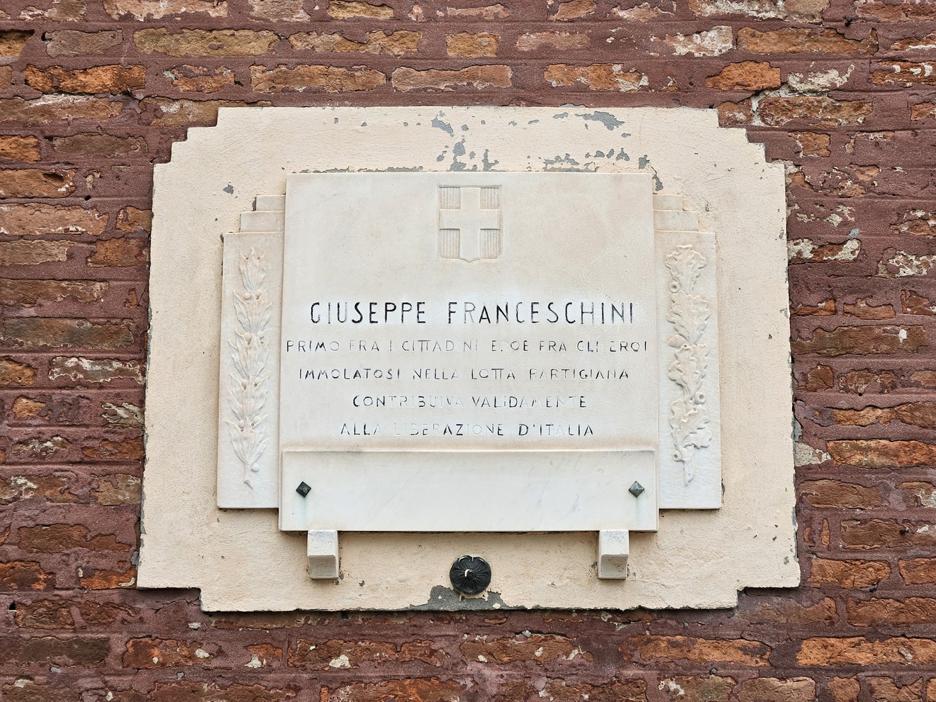 Lapide commemorativa dedicata a Giuseppe Franceschini, situata su un muro di mattoni.