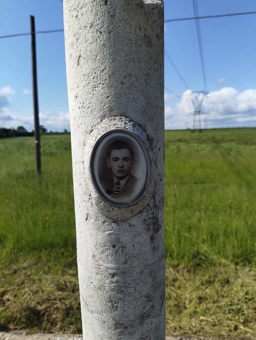 Cippo a Brandoli con una cornice che racchiude una foto in bianco e nero su un palo in un paesaggio verde.
