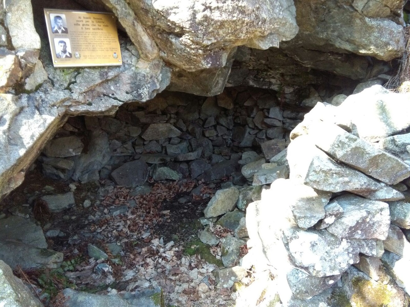 Lapide commemorativa all'ingresso della grotta dei fratelli Besana, immersa nella natura.