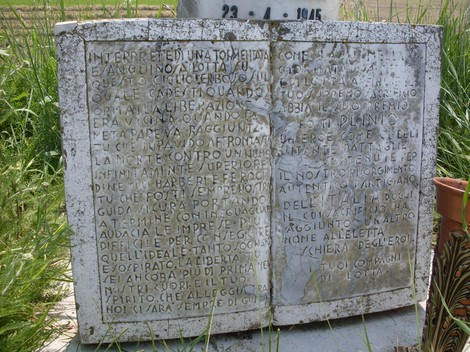 Cippo commemorativo con dediche, immerso nel verde, simbolo di un'importante memoria storica.
