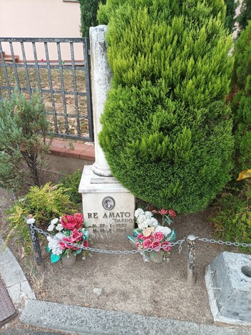 Cippo in pietra con piante ornamentali e fiori decorativi, situato in un'area curata.