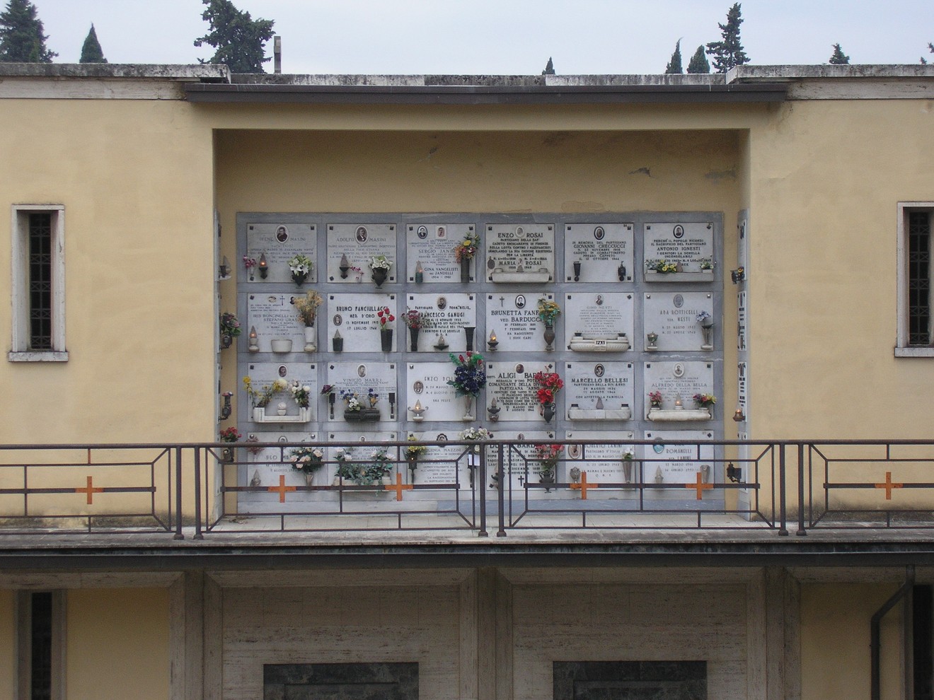 Terrazza dei partigiani: monumento commemorativo con lapidi e fiori in un contesto urbano.