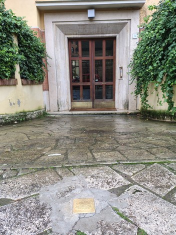 Pietra d'inciampo a Govoni, installazione commemorativa su una pavimentazione di pietra, circondata da vegetazione.