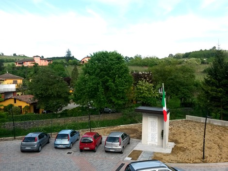 Monumento ai caduti di Torricella Verzate, circondato da verde e auto, simbolo di memoria e rispetto.