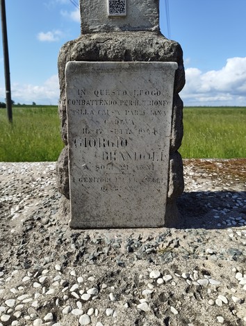 Cippo a Brandoli, monumento commemorativo in una vasta area verde, con nuvole nel cielo.