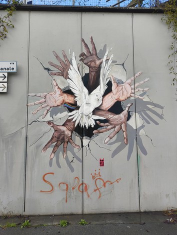 Murale di Pioppe che rappresenta mani e una colomba in un forte messaggio di libertà e unità.