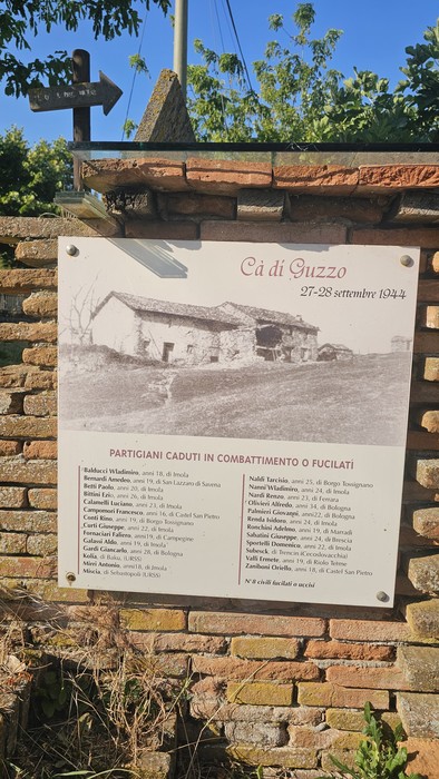 Monumento per Ca' di Guzzo, dedicato ai partigiani caduti, con una foto storica e dettagli commemorativi.