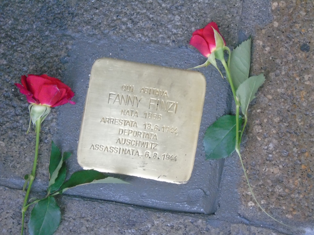 Pietra d'inciampo dedicata a Fanny Finzi, con rose rosse accanto, commemorativa della sua deportazione.
