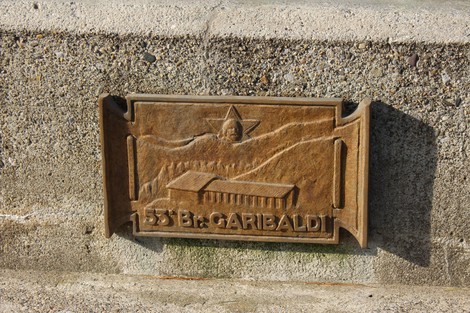 Monumento ai caduti partigiani, con rilievo che raffigura simboli di resistenza e libertà.