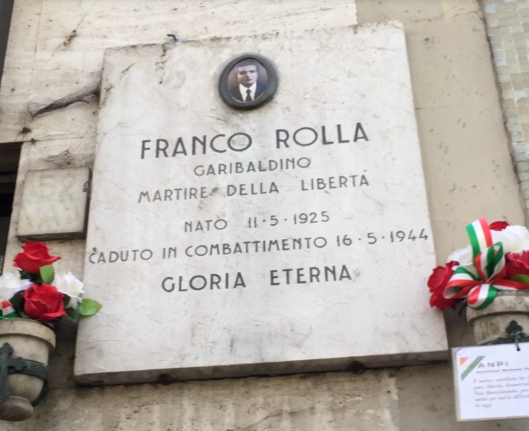 Lapide commemorativa di Franco Rolla, martire della libertà, caduto nel 1944. Decorata con fiori e tricolore.