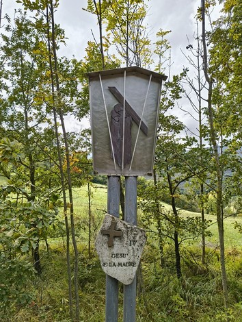 La statua della Via Crucis di Casaglia tra alberi e natura, simbolo di fede e tradizione.