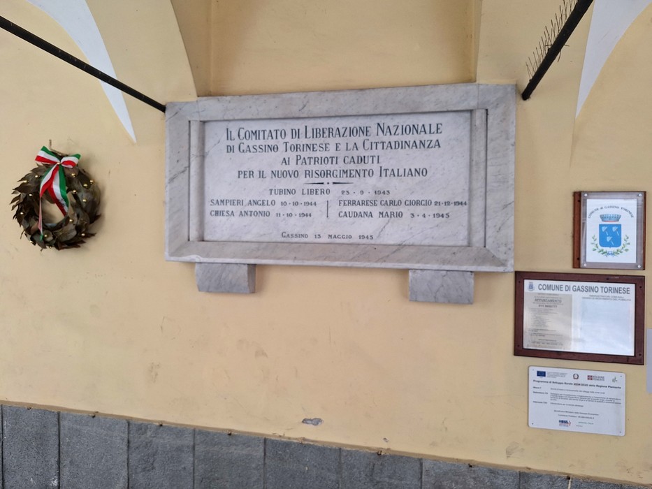 Lapide commemorativa ai patrioti caduti, situata a Cassino, con decorazioni floreali e segni di riconoscimento.
