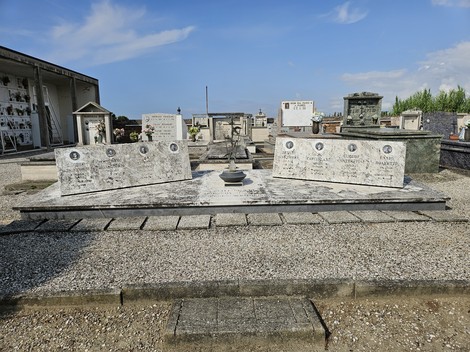 Sacrario dei Partigiani, monumento commemorativo con lapidi in un cimitero, sotto un cielo sereno.