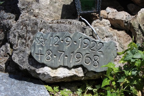 Monumento a Locatelli, lapide commemorativa su una base di pietra, circondata da vegetazione.