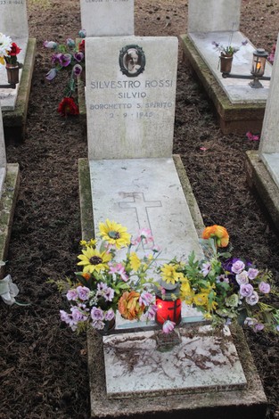 Tombe decorate con fiori e candele in memoria dei caduti per la Libertà in un cimitero.