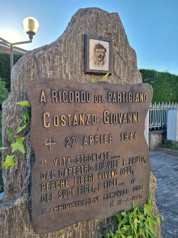 Cippo commemorativo dedicato al partigiano Costanzo Giovanni, con iscrizioni in memoria della sua vita e sacrificio.