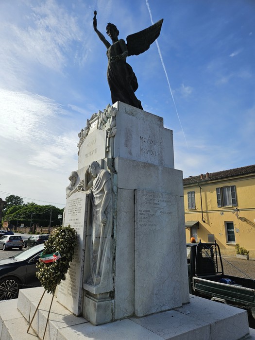 Monumento ai Caduti di San Giovanni in Croce, con statua di un angelo e decorazioni commemorative.