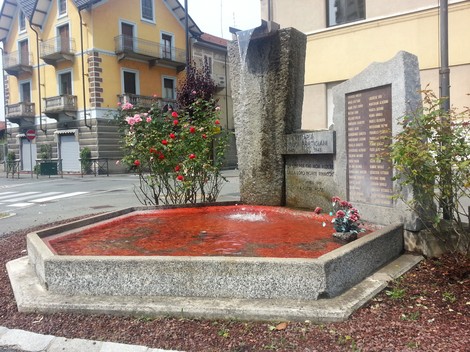 Monumento ai partigiani di Venaria con fontana e piante fiorite in un contesto urbano.