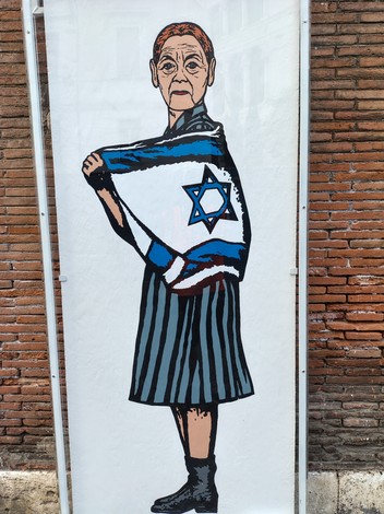Murale che ritrae una figura femminile con una bandiera israeliana, su sfondo di mattoni.