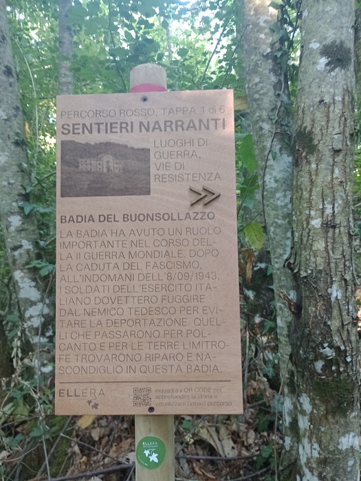 Pannello informativo sui luoghi della Seconda Guerra Mondiale a Monte Senario, circondato da vegetazione.