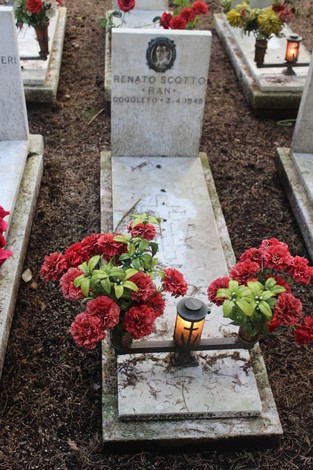 Tombe con fiori rossi e lumini che commemorano i caduti per la Libertà in un cimitero.