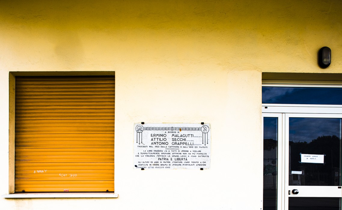 Lapide commemorativa dedicata a Malagutti, Secchi e Grappelli su una parete esterna.