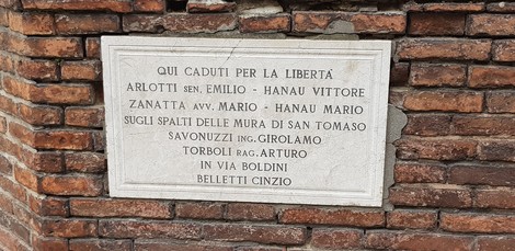 Lapide commemorativa in memoria dei caduti per la libertà, situata su una parete storica.