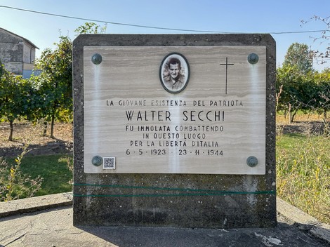 Lapide commemorativa di Walter Secchi, patriota italiano, in un contesto naturale.