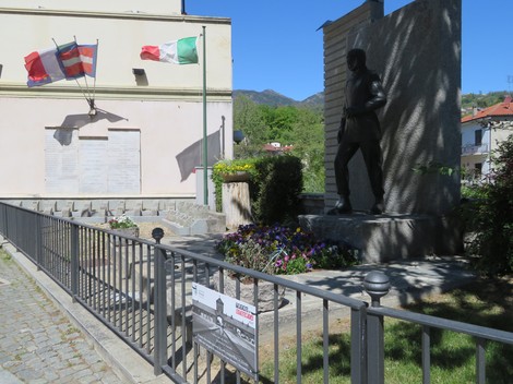 Lapide commemorativa ai caduti di Almese, con statue e decorazioni floreali in un contesto suggestivo.