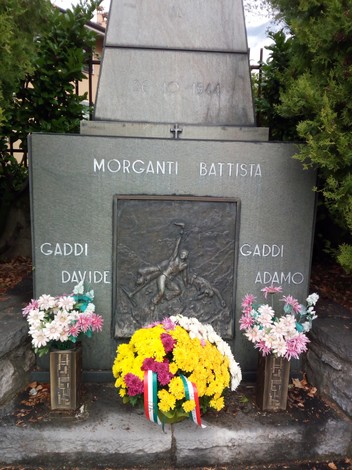 Monumento commemorativo dedicato a Morganti e ai Gaddi, decorato con fiori e alla memoria dei caduti.