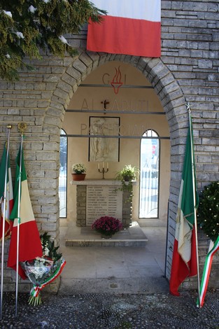 Pietra d'inciampo a Bianchi, monumento commemorativo con bandiere italiane e un'atmosfera solenne.