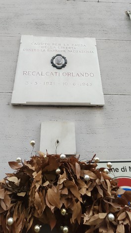 Lapide commemorativa in onore di Recalcati Orlando, con decorazioni floreali.