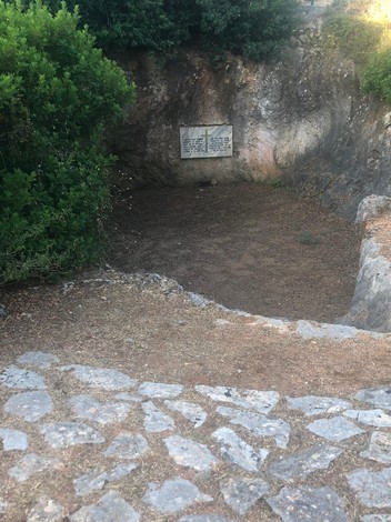 Lapide commemorativa in un'area scavate, circondata da vegetazione e pietre, ricorda gli ufficiali caduti.