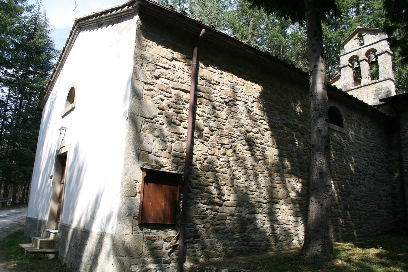 Oratorio di Vallucciole, edificio in pietra immerso nella natura, con campanile e silenziosa atmosfera spirituale.
