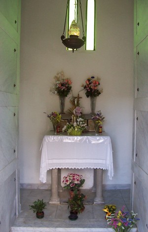 Interno del "Sacrario dei caduti di Soci" con altare, fiori e atmosfera di commemorazione.