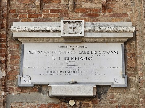 Lapide commemorativa in onore di Pietrobuoni, Barbieri e Bettini, incastonata in un muro di mattoni.
