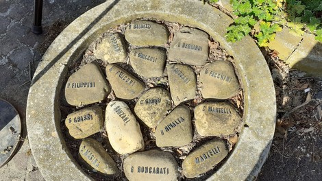 Cippo commemorativo in memoria delle vittime dell'eccidio al pozzo Becca, con incisioni su pietre.